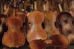Several restored violins are pictured leaning on each other in a pile. Each of the violins carry at least one Star of David