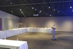 A large room containing a long C-shaped table on the left that can seat around 30 people, facing a podium to the right.