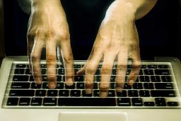 An image of transparent hands hovering over a keyboard.