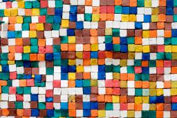 Square tiles of various colours and placed randomly are photographed from above, creating a pixellated effect.