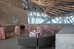 A Tyndall stone terrace is decorated for a reception with light pink satin tablecloths covering cocktail tables and brown leather sofas.