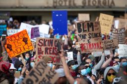 A large group of people holding signs with slogans such as “Black Lives Matter,” “Enough is Enough” and “Your Silence is Betrayal.” 