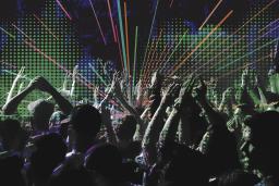 A digital illustration showing a crowd clapping and raising their hands. The background shows a pixelated green soundwave shape and blue and black graffiti-like designs with neon-coloured diagonal lines radiating out from the center.
