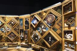 A large art installation composed of hundreds of objects embedded in a cedar frame resembling a quilted blanket.