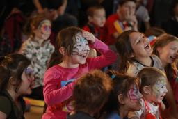 A group of children with playfully painted faces laughing and gesturing.