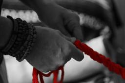 Two hands in black and white hold onto a red rope.