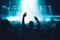 Group of people at a concert with a blue and white light on stage.