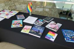 A table with a black tablecloth and colourful books relating to 2SLGBTQI+