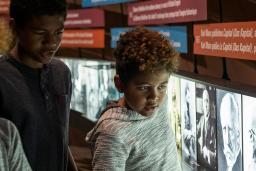 Three young children look at photographs and a text display.