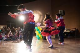 Three dancers in red and white outfits perform in front of a crowd of children at the Canadian Museum for Human Rights.