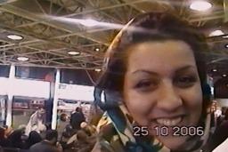 A smiling young woman in a headscarf stands in a crowd. The image has a date-stamp: 25-10-2006.