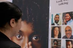 A woman gazes at a display showing faces of a diverse group of people.