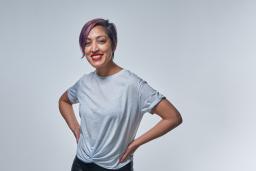 A smiling woman with purple hair wearing a t-shirt.