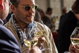 Guests at an event talking and drinking white wine.