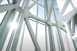 The sun shines through floor-to-ceiling glass windows.