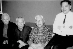 Four men sitting on a couch looking at the Camera. 