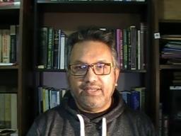 A man sitting in front of a bookshelf.