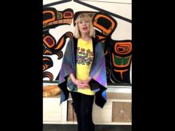 A woman wearing a colourful shirt standing in front of a mural.