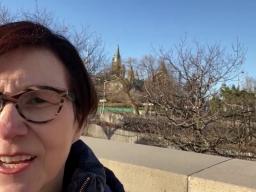 A self-shot photo of a woman looking into the camera, with downtown Ottawa visible behind her.