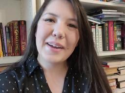 A woman sitting in front of a bookshelf.