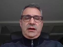 A man wearing glasses sitting at a desk.