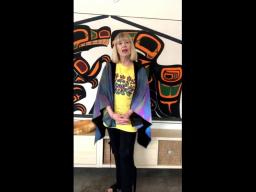 A woman wearing a colourful shirt standing in front of a mural.