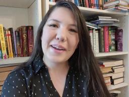 A woman sitting in front of a bookshelf.
