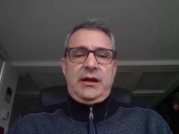 A man wearing glasses sitting at a desk.