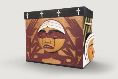 A carved wooden box with the image of an agonized face.