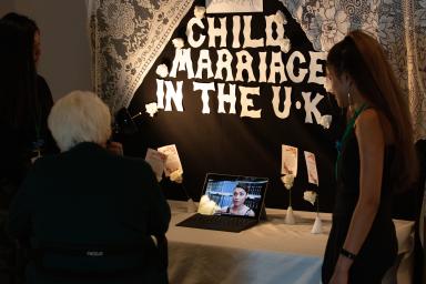 Two students talking about their project, “Child Marriage in the UK,” with a member of the public.