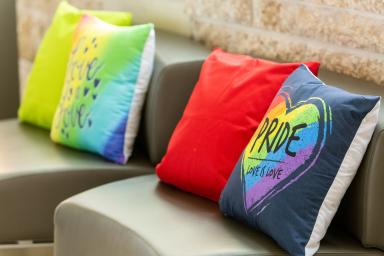 Four colourful cushions on a bench with Pride written on the first one.