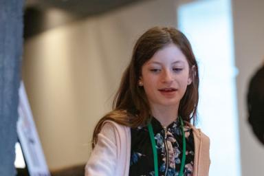 A young girl discusses her project inside a museum gallery.