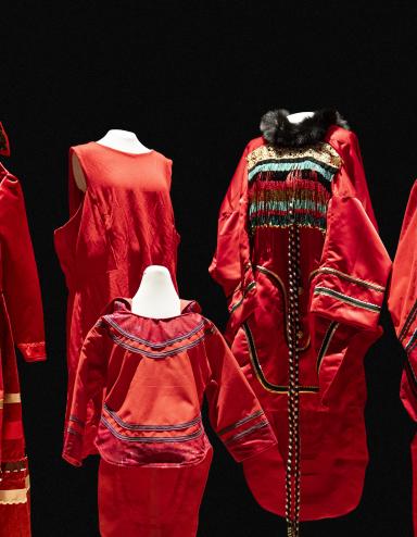 Cinq robes rouges de tailles et de modèles différents sont exposées sur des mannequins. Partially obscured.