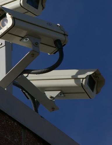 Three surveillance cameras on the corner of a building Partially obscured.
