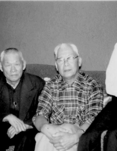 Four men sitting on a couch looking at the Camera. Partially obscured.