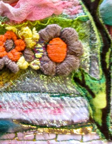 A colourful textile art piece that includes embroidered flowers, branches and greenery mixed with layers of pink, blue and white fabrics. Partially obscured.