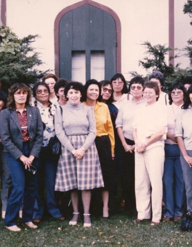 A group of Indigenous women nurses stand together outside.