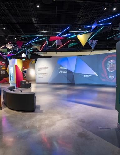 A museum gallery featuring artwork projected onto large screens and colourful geometric shapes.