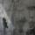 A translucent historical image of a man in a suit layered over a contemporary photo showing the dark outline of two men walking in a triangular hallway.