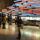 A large number of people in a gallery with a wall of colourful panels and photos showing a timeline of events.