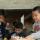 A child reaches into a basket of craft supplies while others work on their projects at a table.