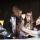 A group of students look at the top of an interactive table emitting white light.