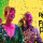 Two people dressed in chic clothes smile as confetti falls on them and hold theatre masks, in front of a colourful background.