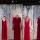 Six red dresses are suspended in air on hangers in front of a backdrop. The backdrop features an image of a birch wood forest with more red dresses hanging in it.
