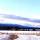 A snow-covered country road with mountains in the background.
