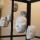 Several white plaster faces hang from strings, inside a cage.