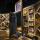 A large, free-standing art installation contains hundreds of objects. It is framed in cedar and there is an open door in the middle that people can walk through.