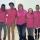 Six teenagers and a middle-aged woman stand with their arms around each other and are smiling for the camera. They are all wearing pink shirts.