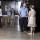 Small groups of people stand in a Museum exhibition space and talk to one another.