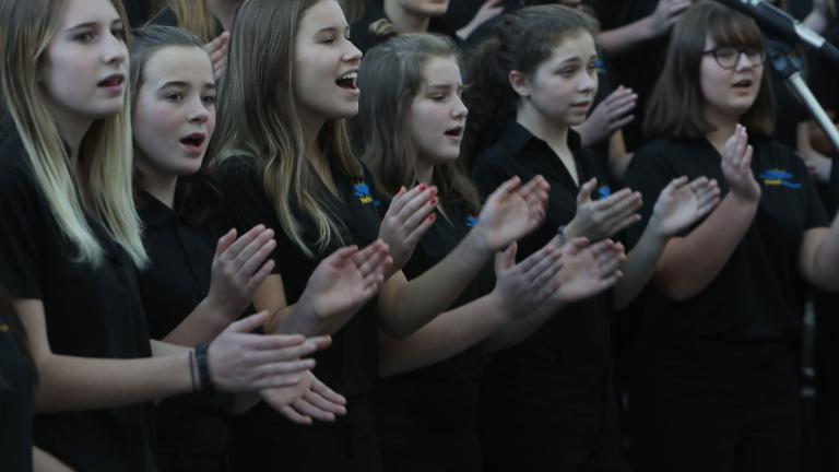 About two dozen youth singing in a choir.